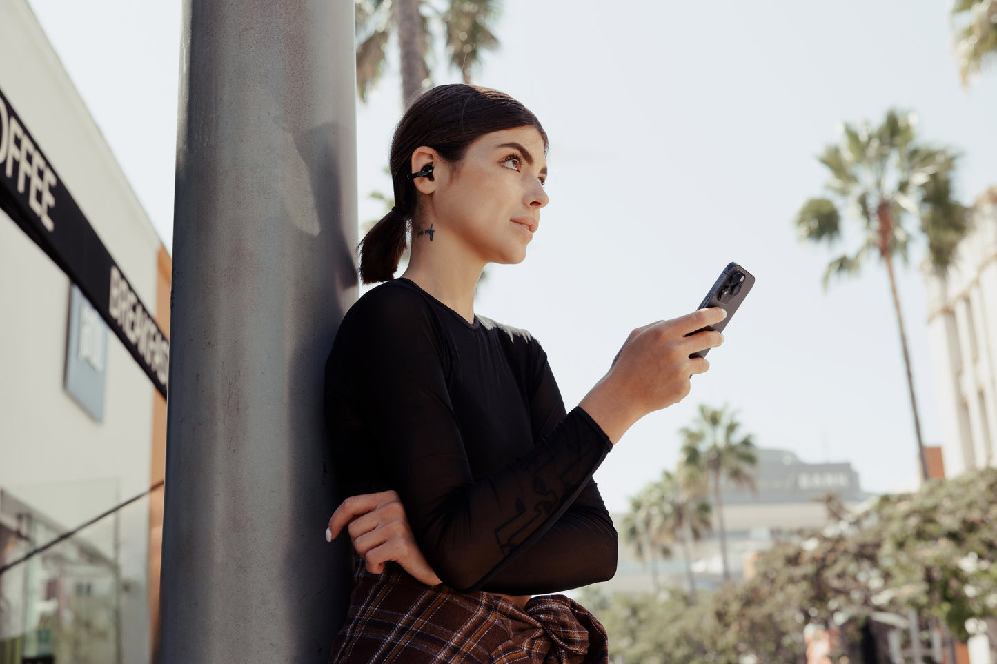 Mujer usando los auriculares Edifier Comfo C en la ciudad mientras escucha música desde su celular