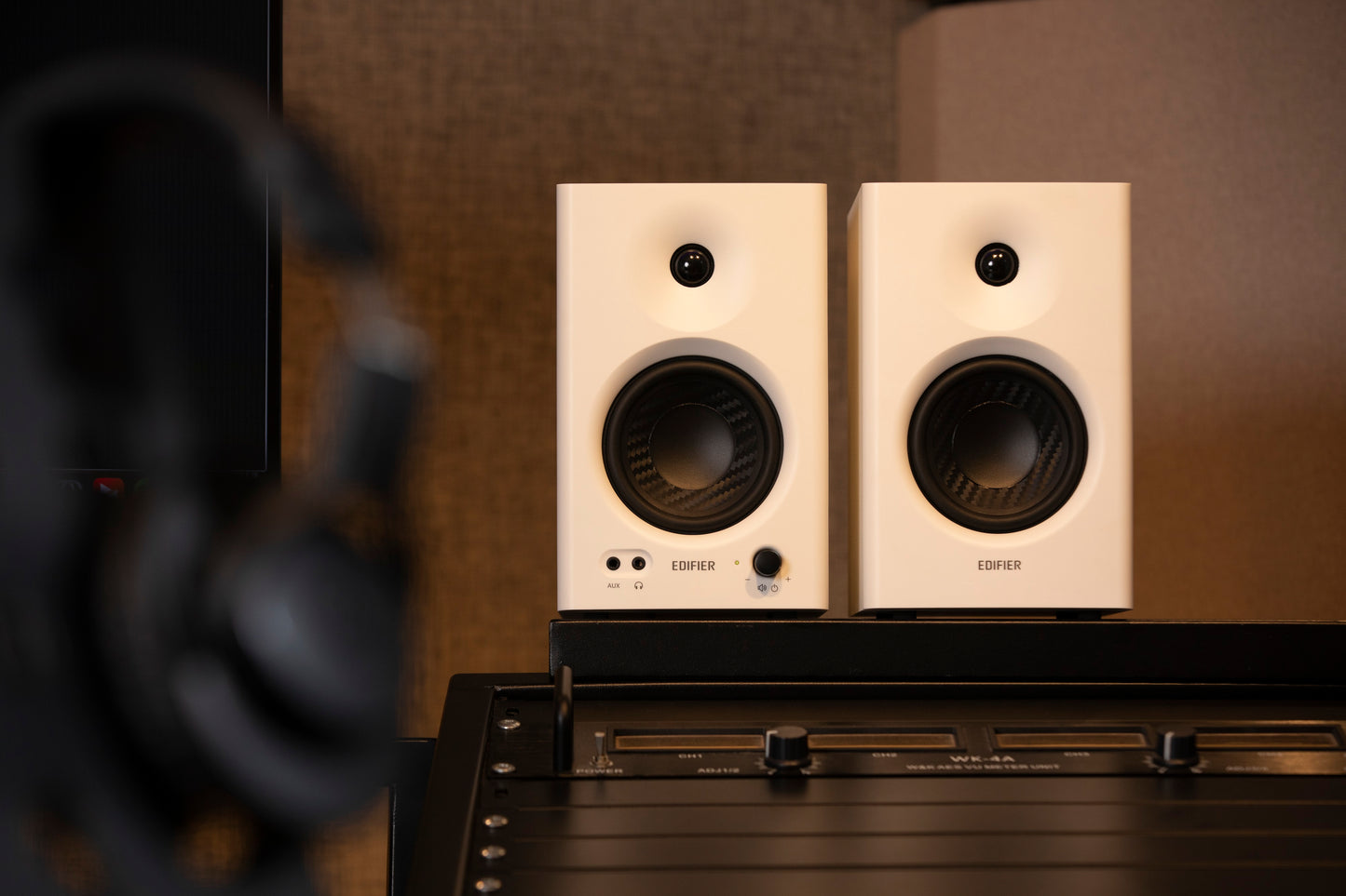 Primer plano de los monitores Edifier MR4 en color blanco sobre consola de mezcla profesional.
