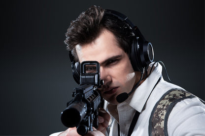 Gamer usando auriculares Edifier G2 II negros mientras apunta con rifle en escena