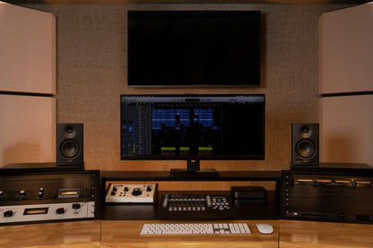 Monitores de estudio Edifier MR4 en color negro, posicionados junto a una pantalla de edición en un setup profesional.